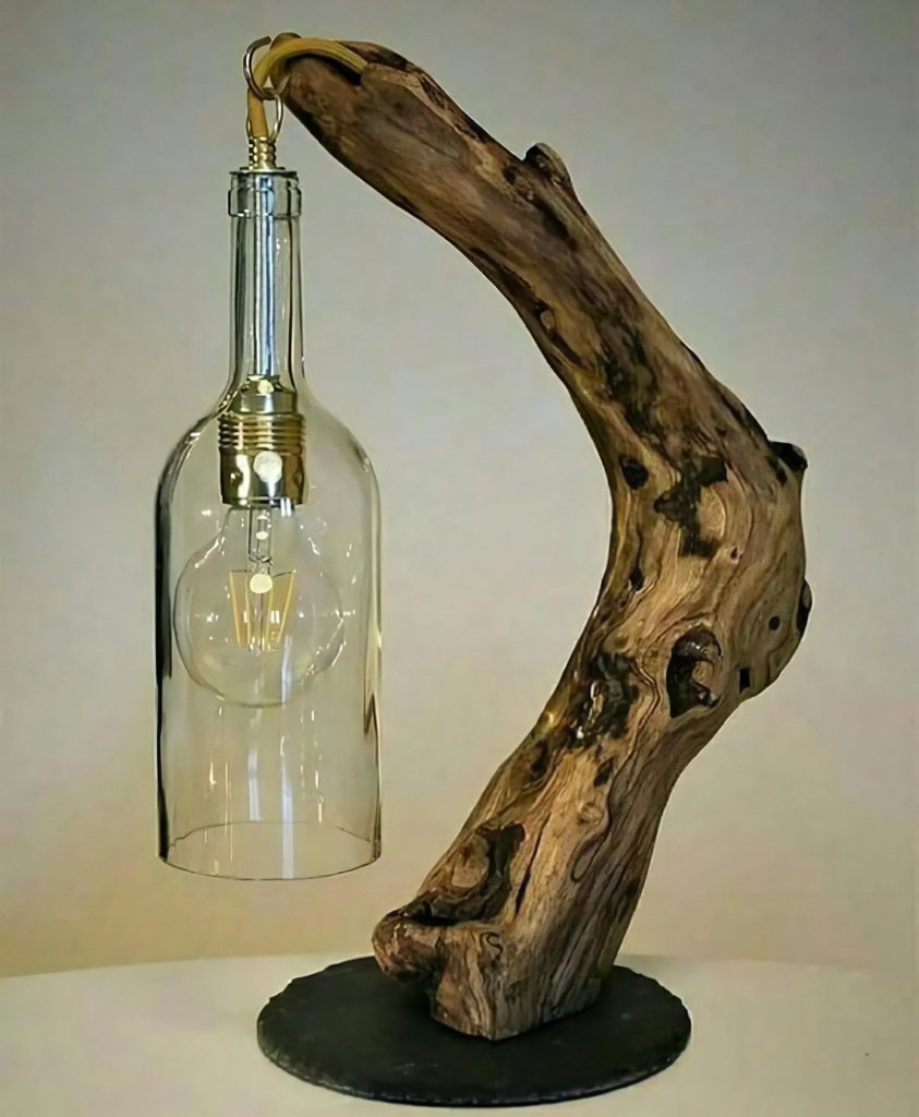 Decorative bottle lamp supported by sculptural driftwood