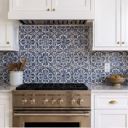 Blue patterned tile backsplash behind a range with white cabinets