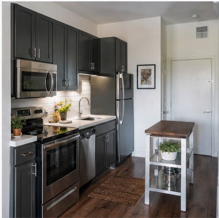 Compact apartment kitchen with charcoal cabinets and a slim movable cart